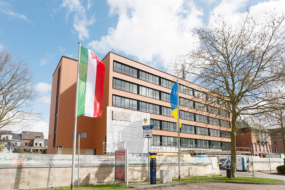 Ein kommunales Gebäude, an dem Baumaßnahmen durchgeführt werden, mit der NRW-Fahne im Vordergrund