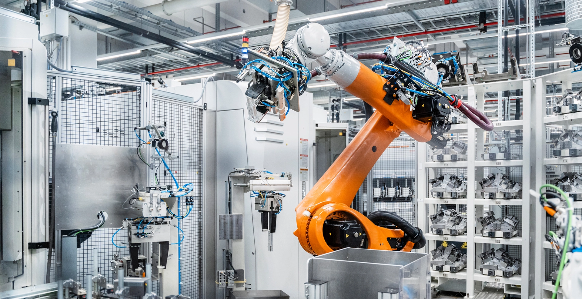 Ein orangefarbener Roboterarm in einer modernen Produktionshalle.