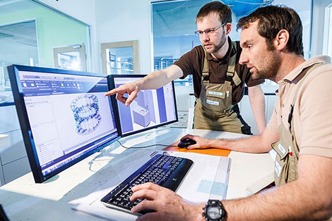 Zwei Männer vor einem Monitor mit einer technischen Zeichnung