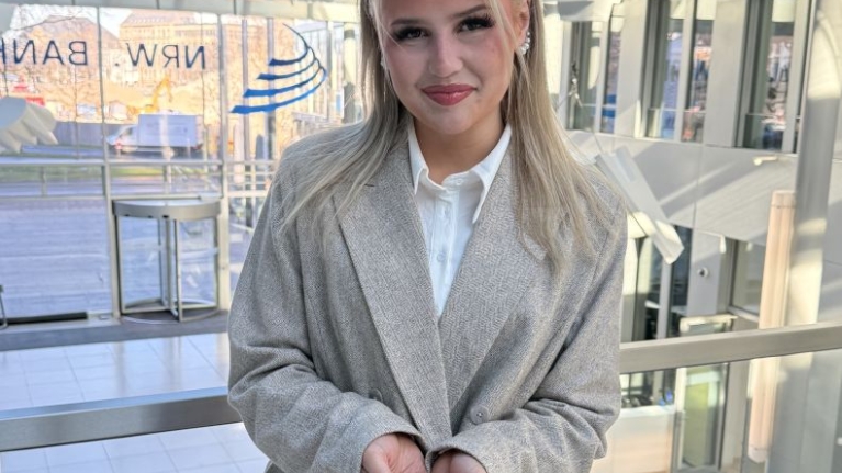 Die Förderberaterin Denise-Sophie Lorenzen zeigt die Geste zum Weltfrauentag 2026 unter dem Motto "Give To Gain".