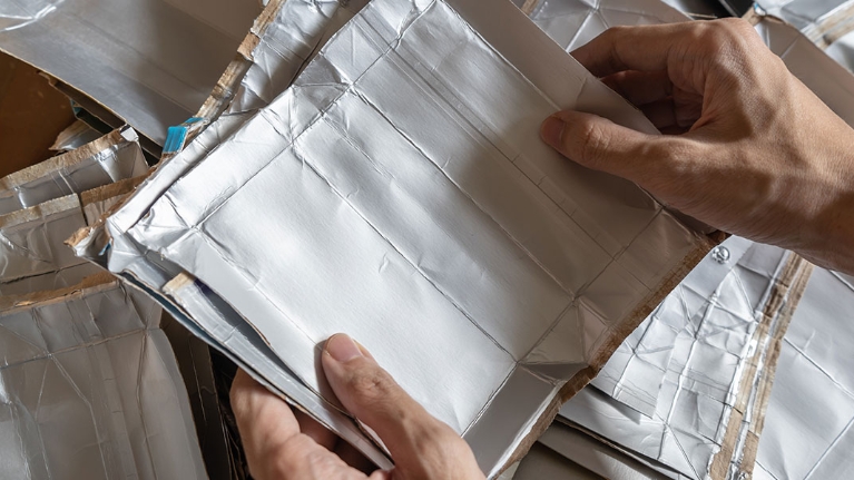 Hände halten auseinander gechnittene, saubere Getränkekartons