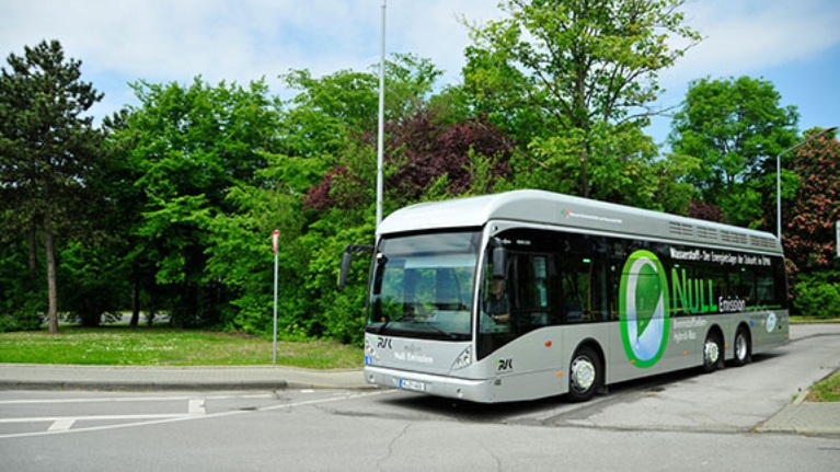 Ein moderner Linienbus, der mit Wasserstoff angetrieben wird, auf einer Straße vor einem Park