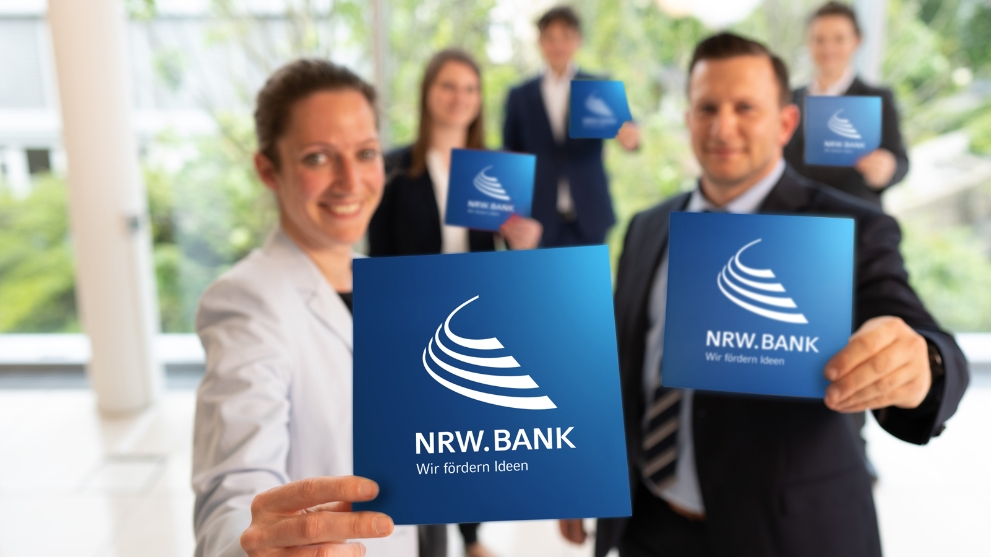 Fünf Mitarbeiterinnen und Mitarbeiter der NRW.BANK heißen neue Kolleginnen und Kollegen herzlich willkommen.
