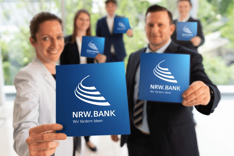 Fünf Mitarbeiterinnen und Mitarbeiter der NRW.BANK heißen neue Kolleginnen und Kollegen herzlich willkommen.