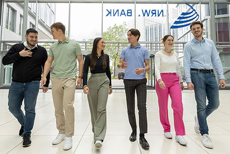 Sechs junge Erwachsene laufen durch das helle Foyer der NRW.BANK in Düsseldorf.