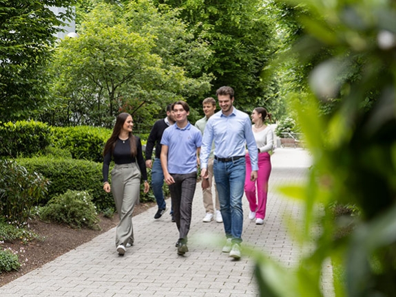 Eine Gruppe dual Studierenden spaziert durch einen Park.