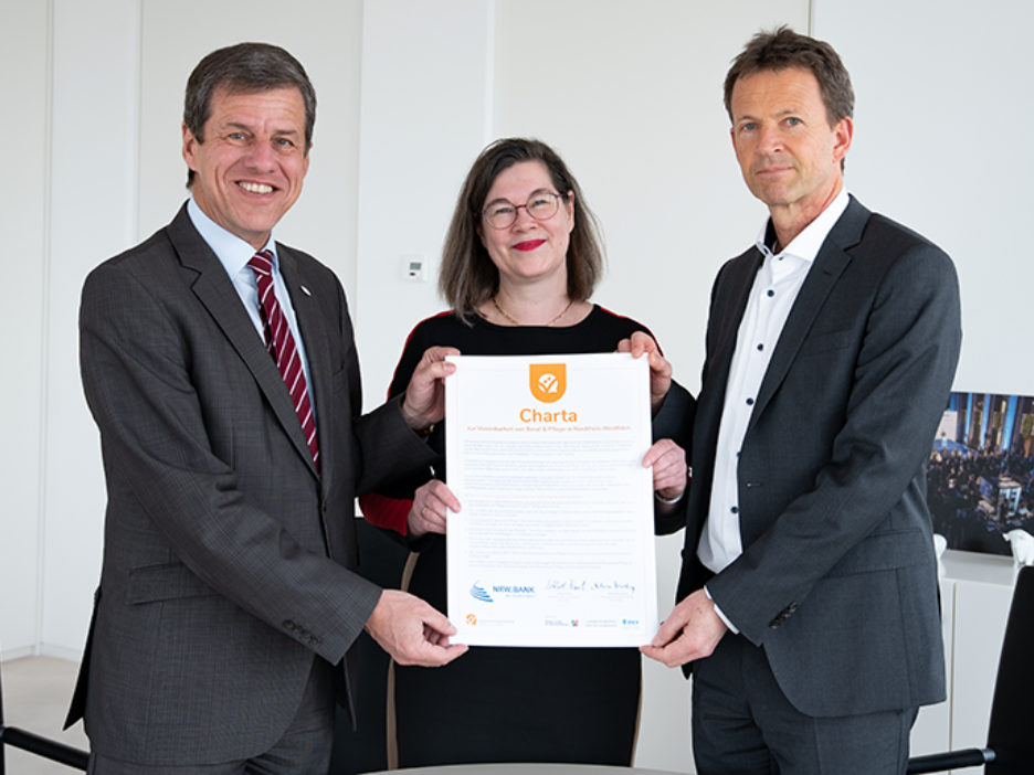 NRW.BANK-Vorstandsvorsitzender Eckhard Forst, Regine Jäger (Ansprechpartnerin für Beruf und Familie) und Achim Meierkamp, Bereichsleiter Personal, halten die unterzeichnete Charta für Beruf und Pflege.