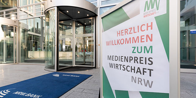 Ein Schild der steht vor dem Gebäude der NRW.BANK mit der Aufschrift: Herzlich willkommen zum MEDIENPREIS WIRTSCHAFT NRW