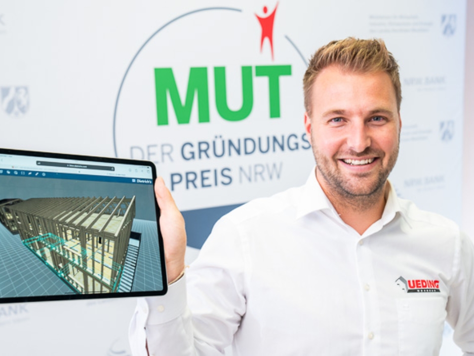 Manuel Ueding von Ueding Wohnbau vor dem MUT - DER GRÜNDUNGSPREIS NRW-Logo