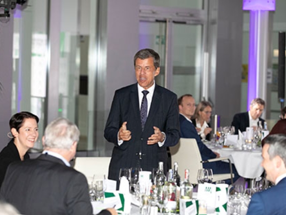 NRW.BANK-Vorstandsvorsitzender Eckhard Forst hält, an einem festlich gedeckten Tisch stehend, eine Rede.