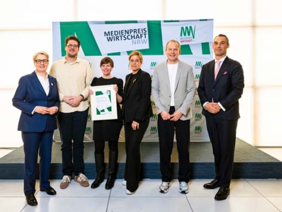 Der Sonderpreis für besondere multimediale Umsetzung (1.000 Euro) geht an Philipp Blanke (2.v. l.), Till Hafermann (nicht im Bild), Jan Knoff und Claudia Wiggenbröker. Sie erhalten die Auszeichnung von Gabriela Pantring, designierte Vorsitzende des Vorstands der NRW.BANK, Wirtschafts- und Klimaschutzministerin Mona Neubaur und Daniel Schleimer von VSU Wachdienst Rhein-Ruhr (Bild: NRW.BANK / Oliver Wachenfeld)
