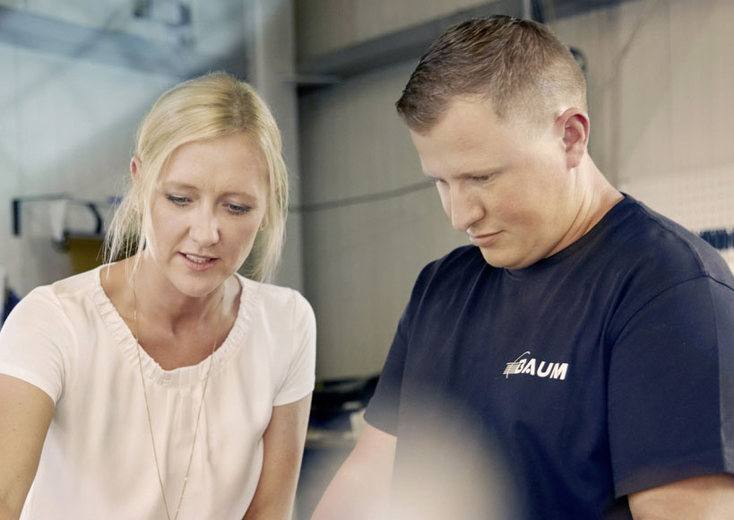Melanie Baum und ein Mitarbeiter unterhalten sich in einer Produktionshalle