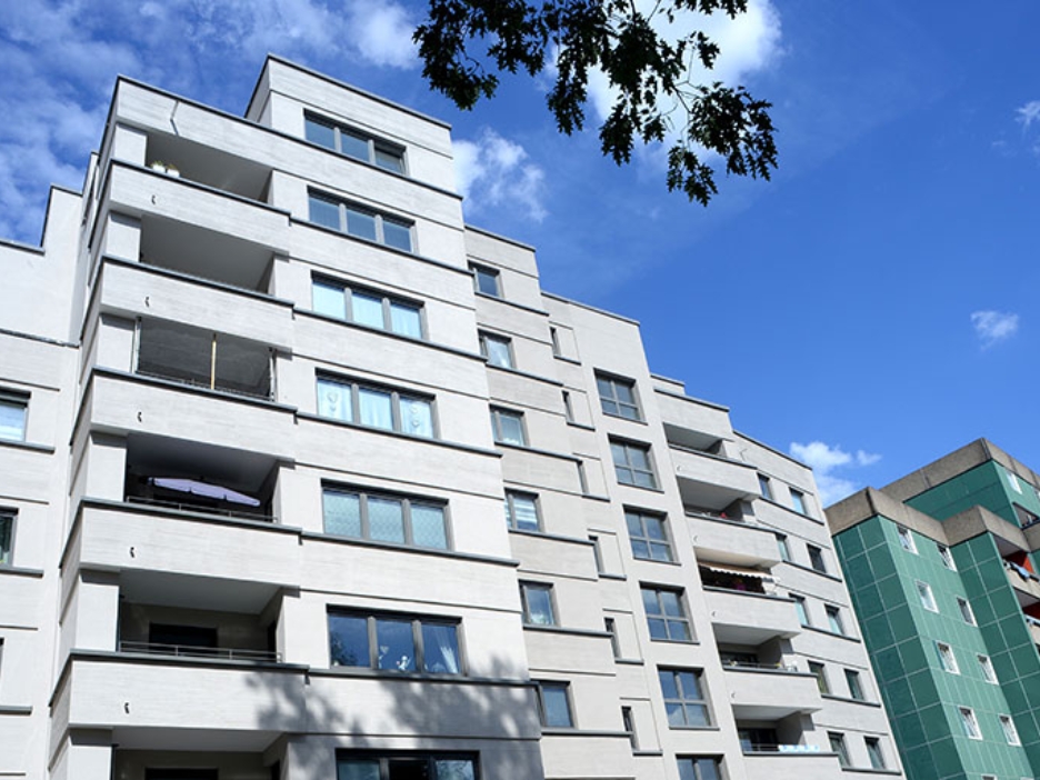 Moderne Wohnanlage mit klar strukturierten Fassaden und Balkonen unter blauem Sommerhimmel.