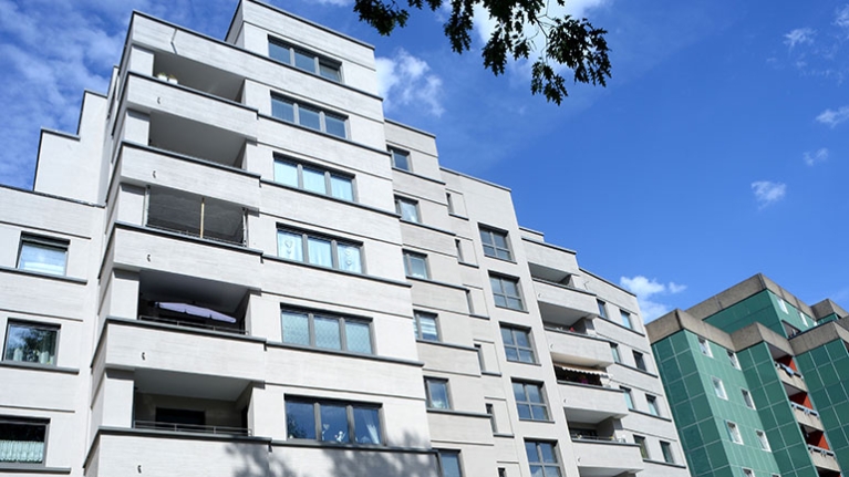 Moderne Wohnanlage mit klar strukturierten Fassaden und Balkonen unter blauem Sommerhimmel.