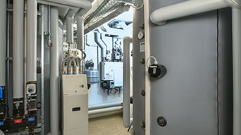 Technikraum mit Leitungen, Wärmepumpen und großen Pufferspeichern.