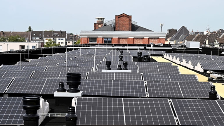 Große Solarfläche auf Flachdach im Clouth-Quartier, umgeben von Wohnhäusern.
