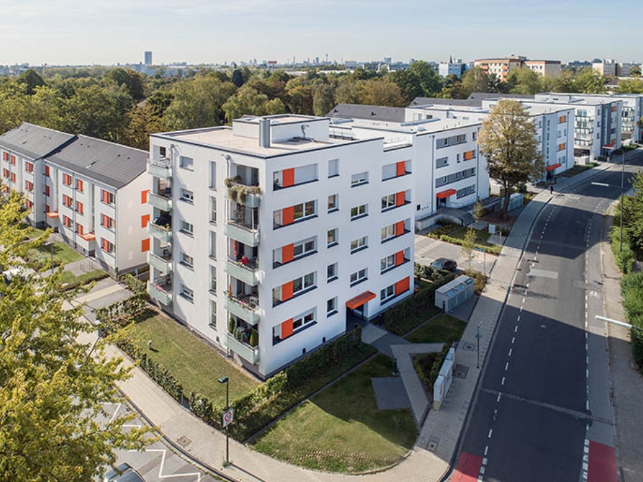 Wohnanlage aus 7 Mehrfamilienhäusern mit Vorgärten und Bäumen im Hintergrund