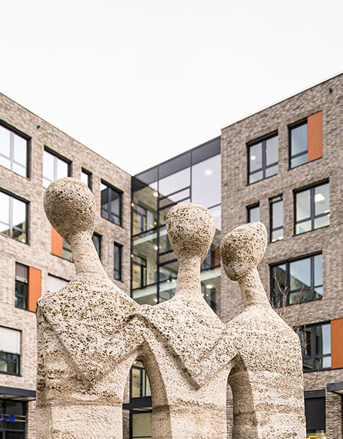 Steinernes Standbild vor einem modernen Gebäudekomplex