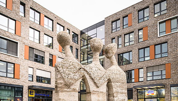 Steinernes Standbild vor einem modernen Gebäudekomplex