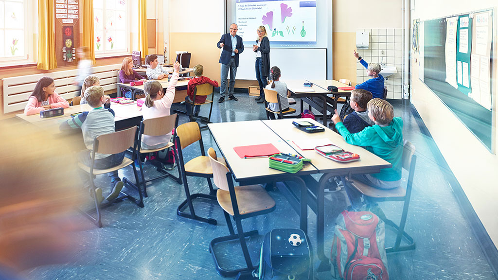 Unterrichtsraum einer Schule mit lernenden Schülern an drei Tischen