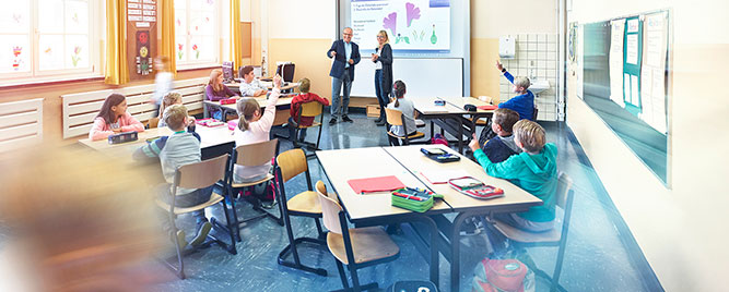 Unterrichtsraum einer Schule mit lernenden Schülern an drei Tischen