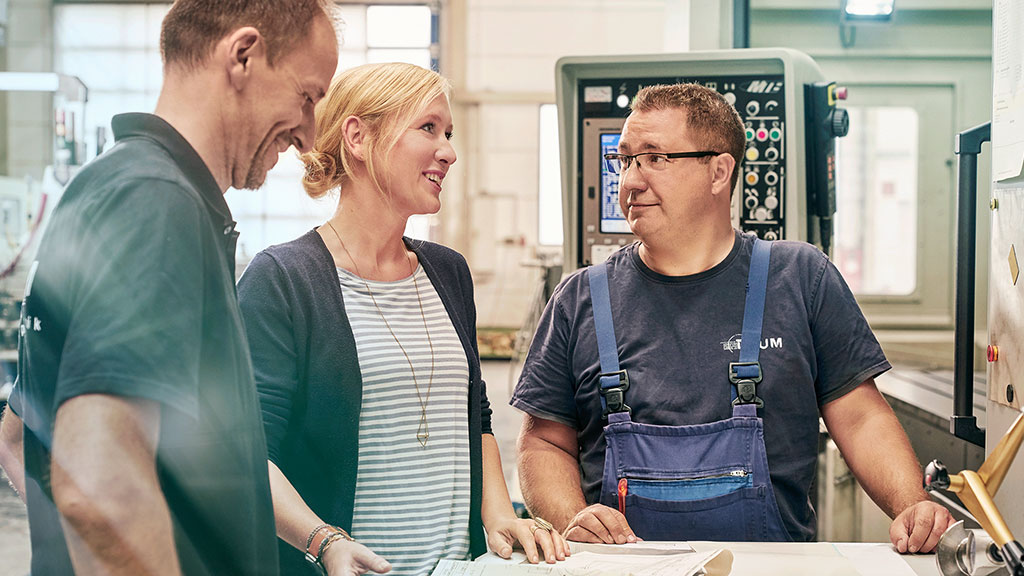 Unternehmerin Melanie Baum mit zwei Mitarbeitern in der Werkstatt