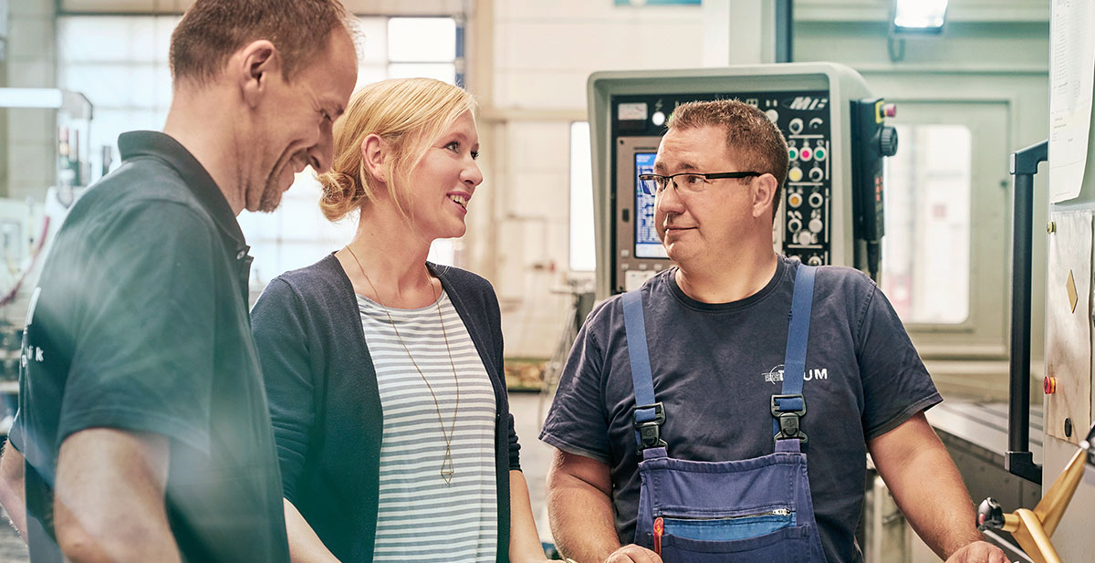 Unternehmerin Melanie Baum mit zwei Mitarbeitern in der Werkstatt