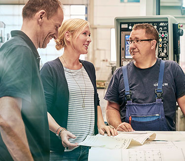 Unternehmerin Melanie Baum mit zwei Mitarbeitern in der Werkstatt