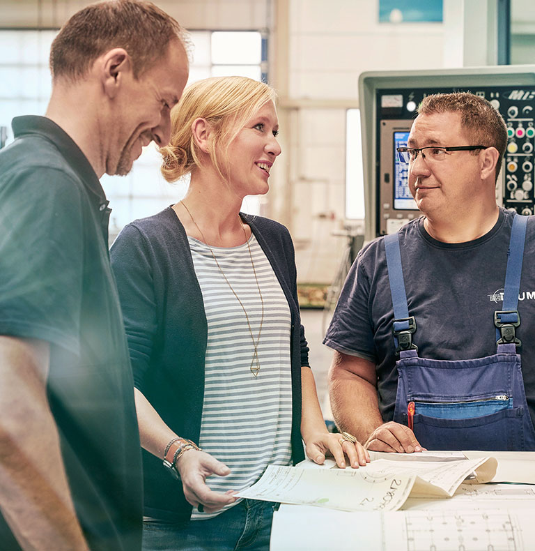 Unternehmerin Melanie Baum mit zwei Mitarbeitern in der Werkstatt