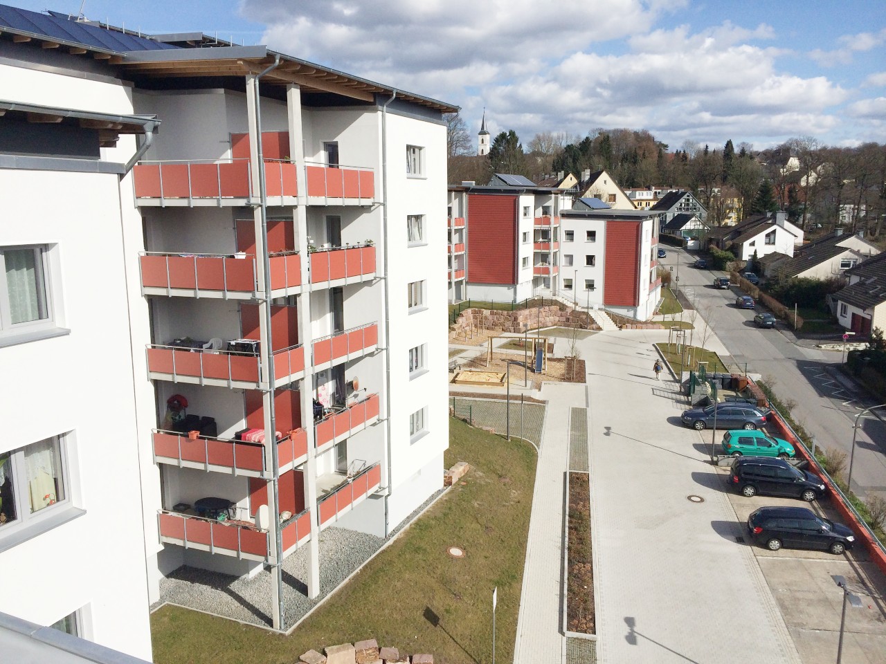 Ein modernes Wohnquartier, davor eine kleine Grünfläche und ein Parkplatz