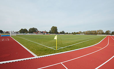 Fußballplatz, außen herum eine rote Laufbahn