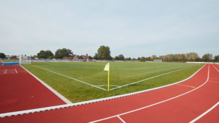 Fußballplatz, außen herum eine rote Laufbahn