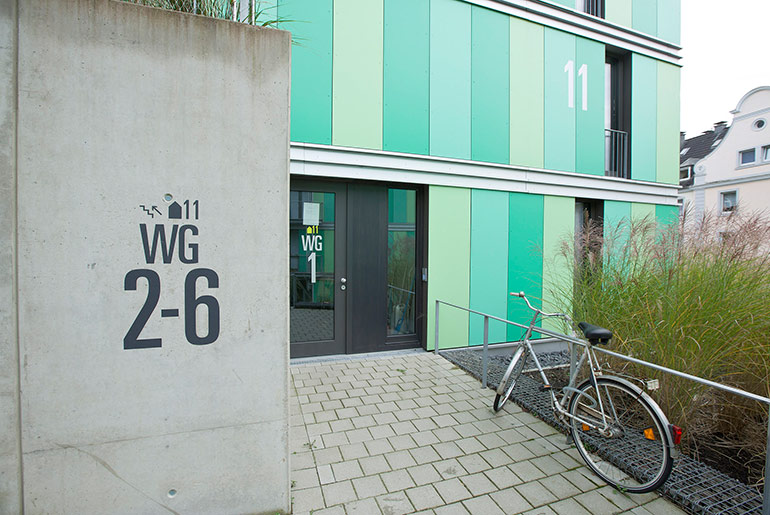 Der Eingangsbereich des Studentenwohnheims Wuppertal, grüne Fassade, vor der Tür steht ein Fahrrad
