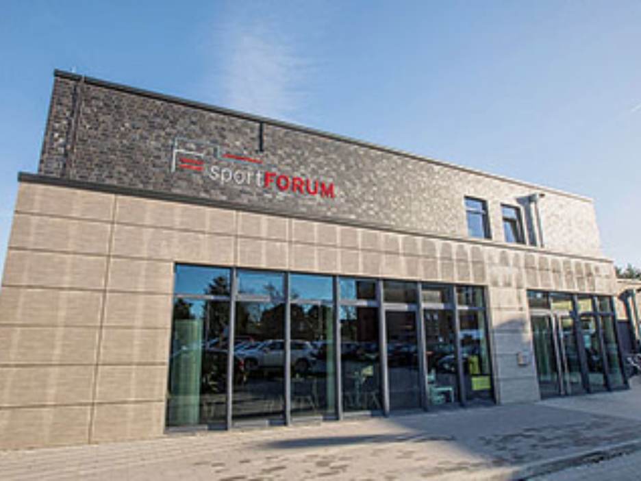Außenansicht des sportFORUMs Rheine: Graue Fassade, Fensterfront und Schriftzug Sport Forum