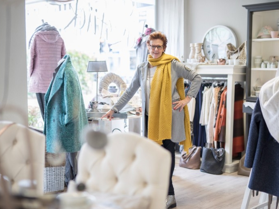 Petra Hustadt steht in ihrem Geschäft Herzstück umgeben von Kleidung und Wohnaccessoires