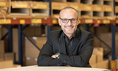 Frank Großmann, Geschäftsführer von MarpaJansen steht in seiner Lagerhalle und lächelt in die Kamera