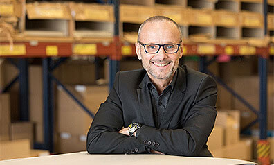 Frank Großmann, Geschäftsführer von MarpaJansen steht in seiner Lagerhalle und lächelt in die Kamera