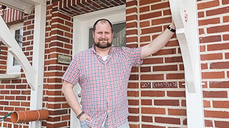 Sebastian Haverkotte steht vor dem Eingangsbereich seines Hauses mit roter Backsteinfassade