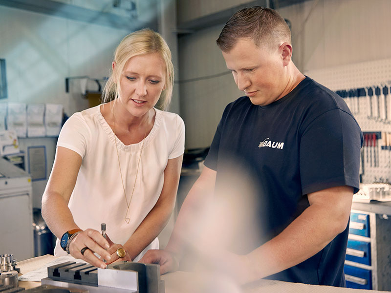 Melanie Baum und Mitarbeiter begutachten ein Bauteil in ihrer Werkstatt.