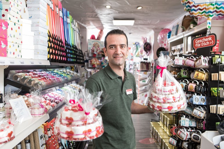 Ein Mann präsentiert in einem Candy-Shop als Präsent verpackte Torten aus Süßigkeiten.