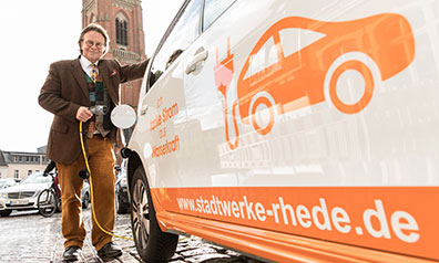 Ronald Heinze, Geschäftsführer der Stadtwerke Rhede, schließt ein E-Auto an die Ladestation an.