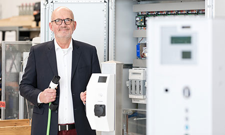 RTB-Geschäftsführer Rudolf Broer vor einer Ladestation mit Stromkabel in der Hand