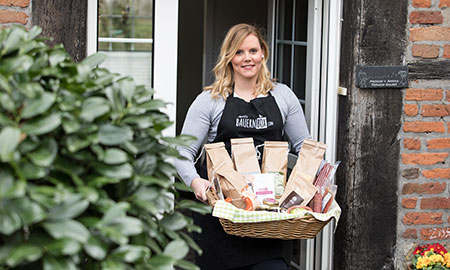 Annika Ahlers, Gründerin von Bauernbox, hält einen Korb mit Lebensmitteln in den Händen.