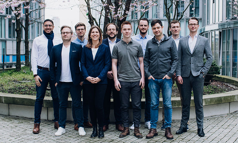 Das Team von Taxy.io: Gruppenfoto mit 10 Mitarbeitern vor dem Bürogebäude