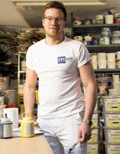 Malermeister Marc Tensi weiß gekleidet in seinem Materiallager