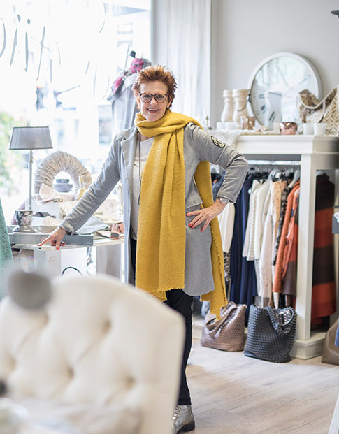 Petra Hustadt in Ihrem Geschäft Herzstück, umgeben von Kleidung und Wohnaccessoires