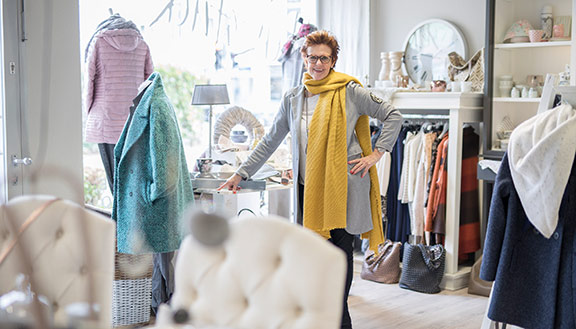 Petra Hustadt in Ihrem Geschäft Herzstück, umgeben von Kleidung und Wohnaccessoires