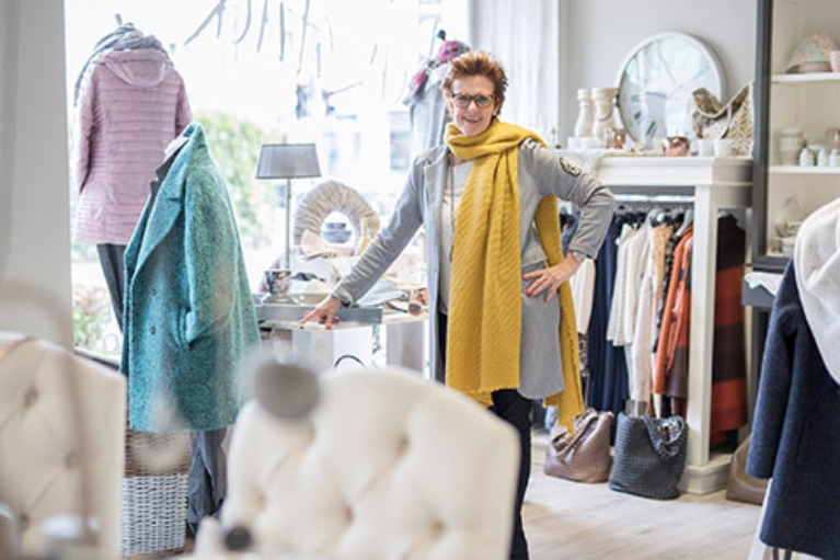 Petra Hustadt in Ihrem Geschäft Herzstück, umgeben von Kleidung und Wohnaccessoires