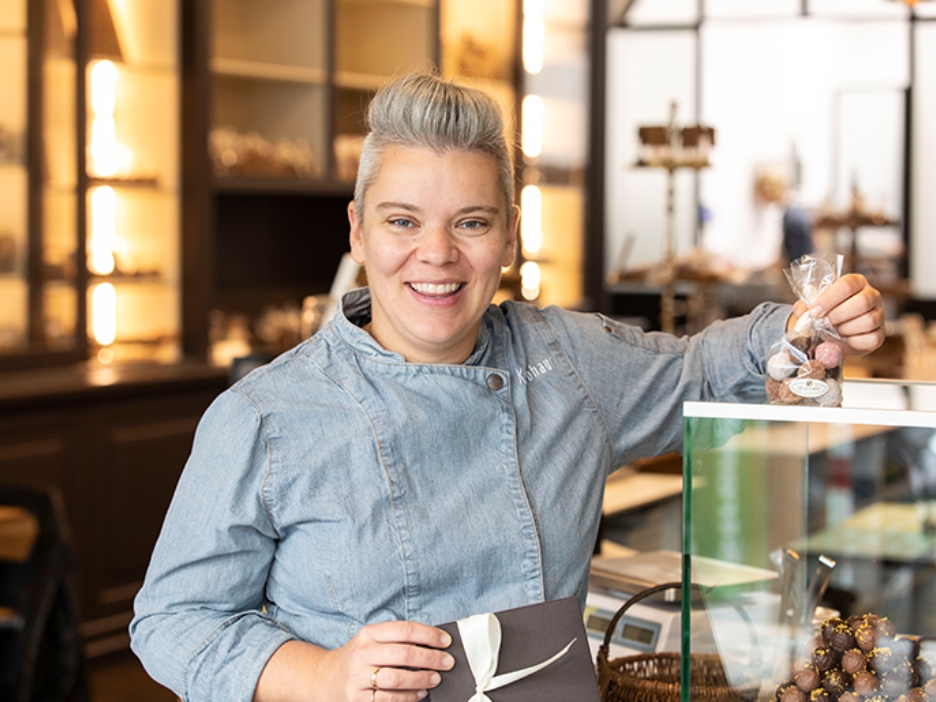 Die junge Konditorin Lathrin Lohaus steht in ihrem Cafe mit einer Packung Pralinen neben dem Tresen.