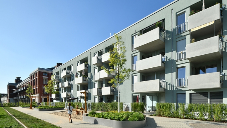 Hausfassade des neuen Clouth Quartiers mit Balkonen und einem Spielplatz